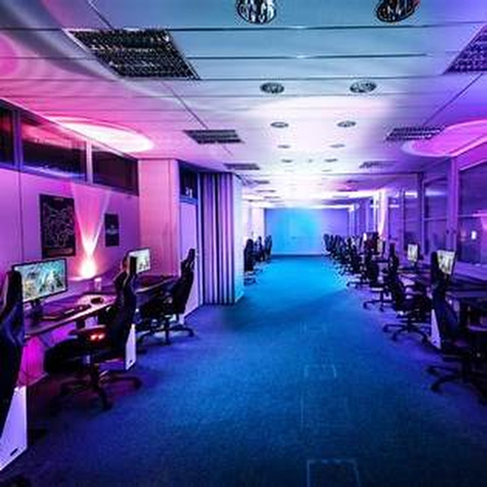 Grande salle remplie de postes de jeu éclairés au néon